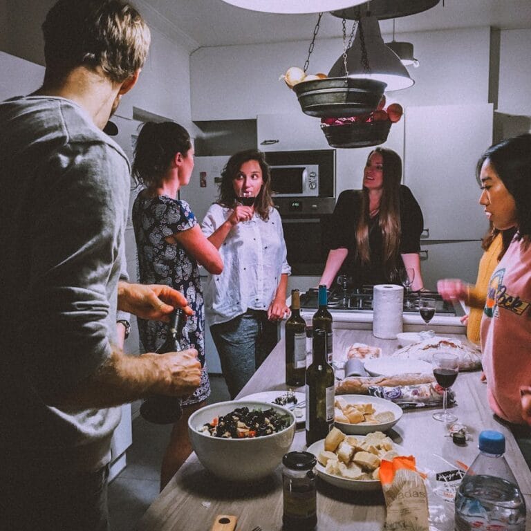 A group of adults enjoying a casual dinner party in a cozy, modern kitchen setting.