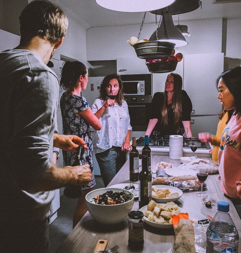 A group of adults enjoying a casual dinner party in a cozy, modern kitchen setting.