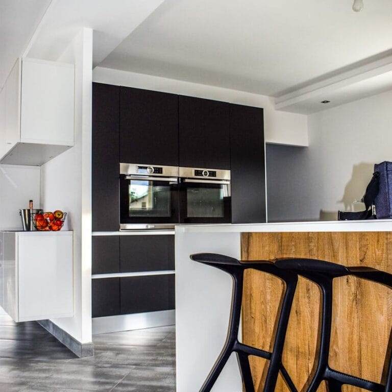 A contemporary kitchen featuring sleek cabinetry and elegant bar stools in a minimalist design.